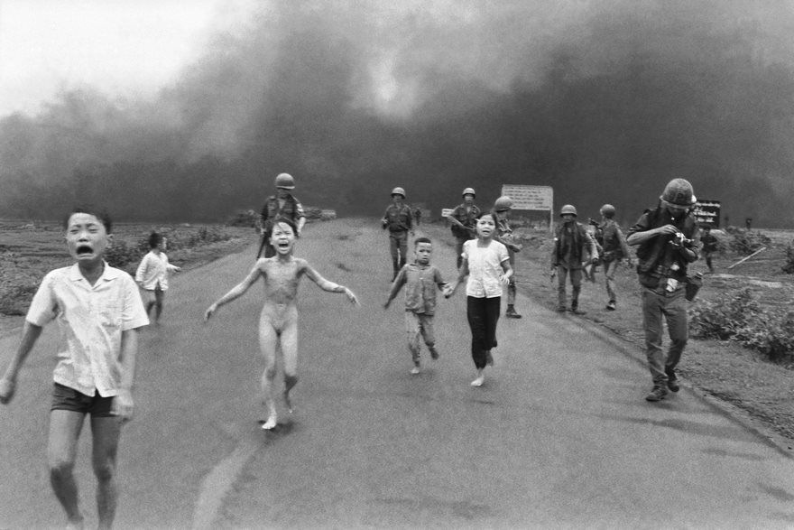 Sør-vietnamesiske styrker følger etter livredde barn, inkludert 9 år gamle Kim Phuc i sentrum, da de løper nedover rute 1 nær Trang Bang etter et napalmangrep fra luften på mistenkte Viet Cong-skjulesteder, 8. juni 1972. Et sørvietnamesisk fly ved et uhell droppet sin flammende napalm på sørvietnamesiske tropper og sivile. Den livredde jenta hadde revet av seg de brennende klærne mens hun flyktet. Barna fra venstre til høyre er: Phan Thanh Tam, yngre bror til Kim Phuc, som mistet et øye, Phan Thanh Phouc, yngste bror til Kim Phuc, Kim Phuc og Kim